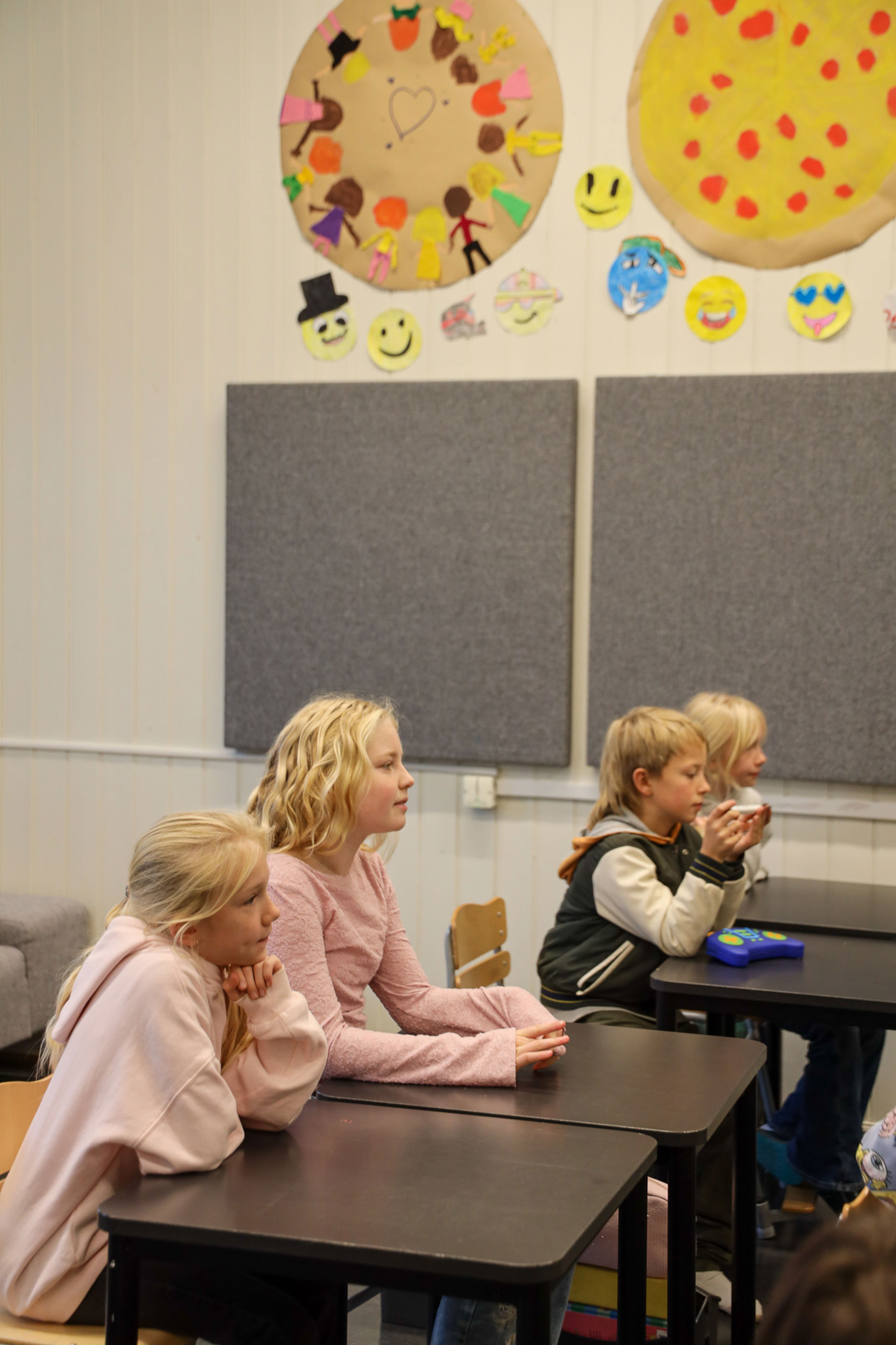 en gruppe barn som sitter ved pulter i et klasserom en gruppe barn som sitter ved pulter i et klasserom