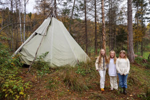 en gruppe personr som står foran et telt i skogen