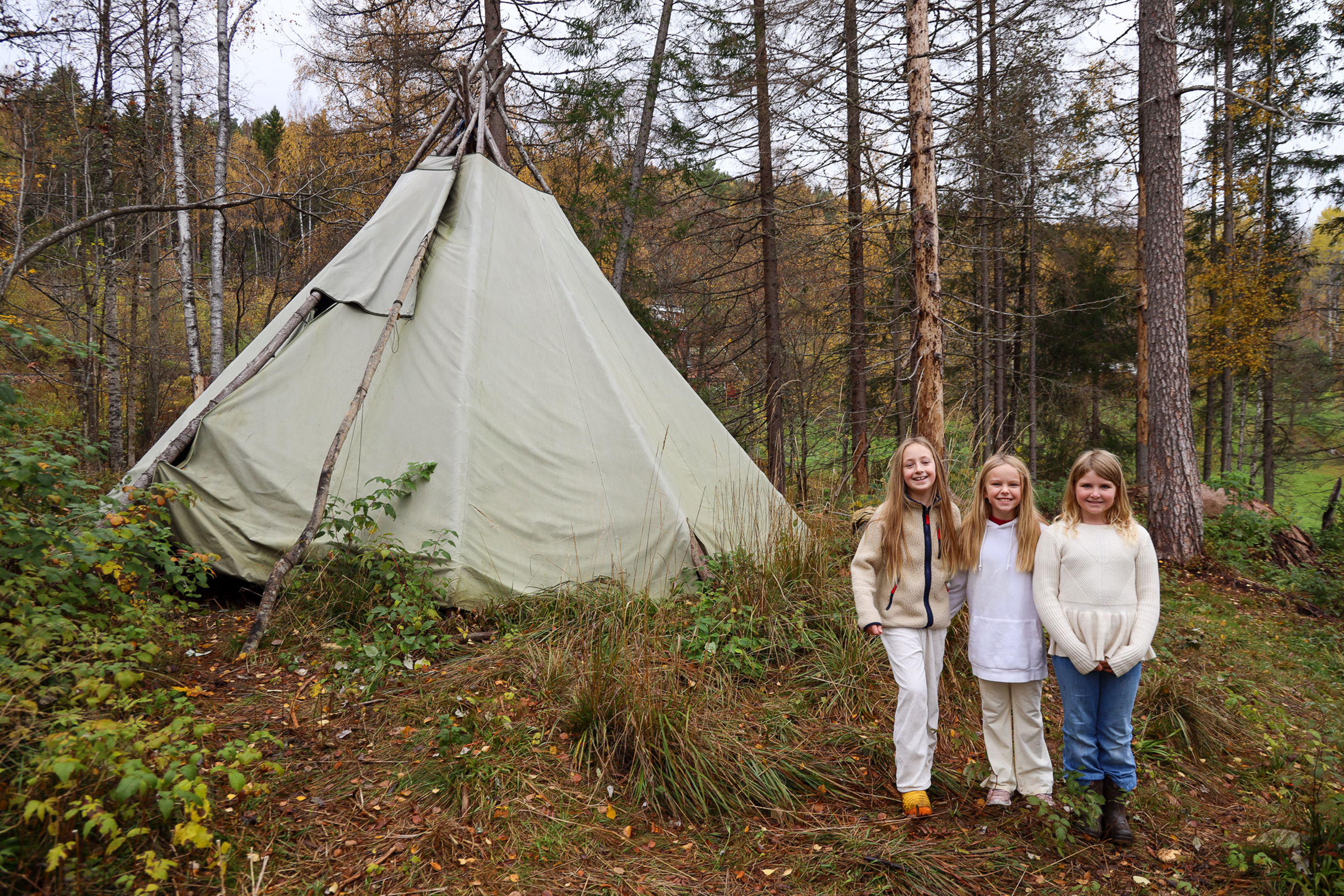 en gruppe personr som står foran et telt i skogen en gruppe personr som står foran et telt i skogen